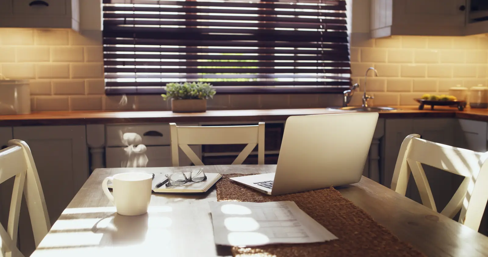 A kitchen table with a laptop and paperwork